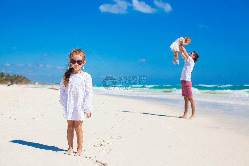 年轻父亲和他的可爱女儿在白沙滩玩得开心图片