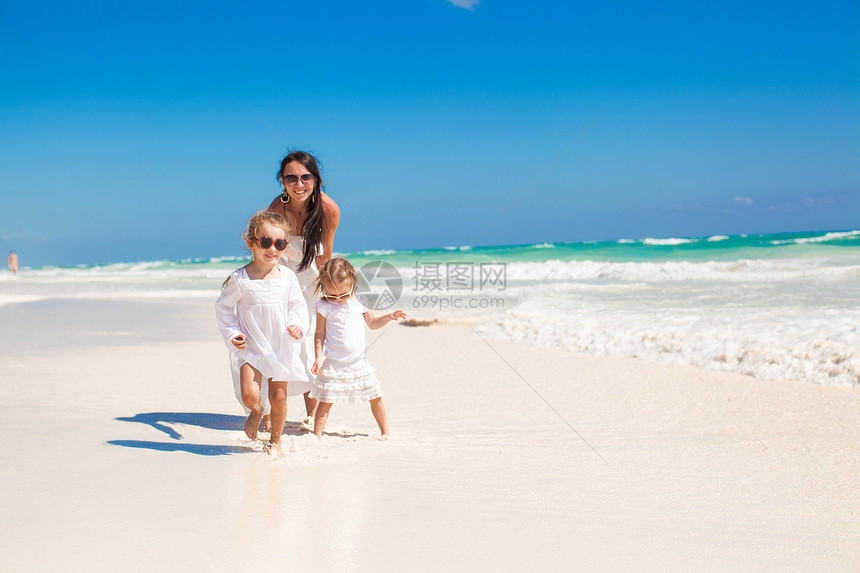 年轻母亲及其女儿们在热带白沙滩上行走图片