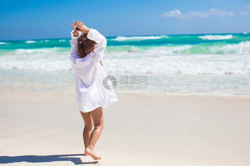 可爱的小女孩在阳光明媚时 在奇异白沙滩上跳舞图片