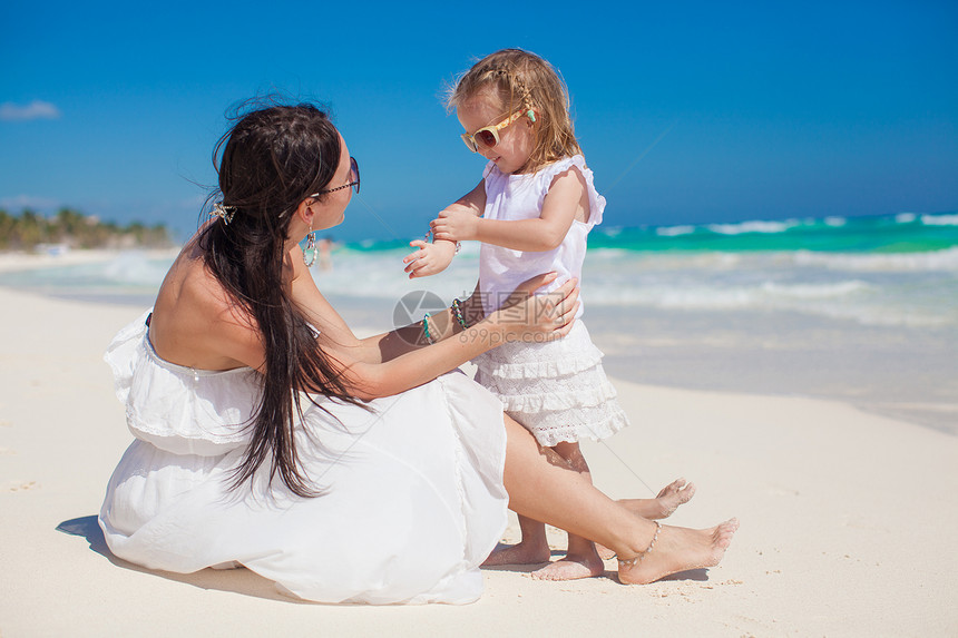 可爱的小女孩和妈妈在白沙上玩得开心微笑海岸女士乐趣情调婴儿女性父母女儿海岸线图片