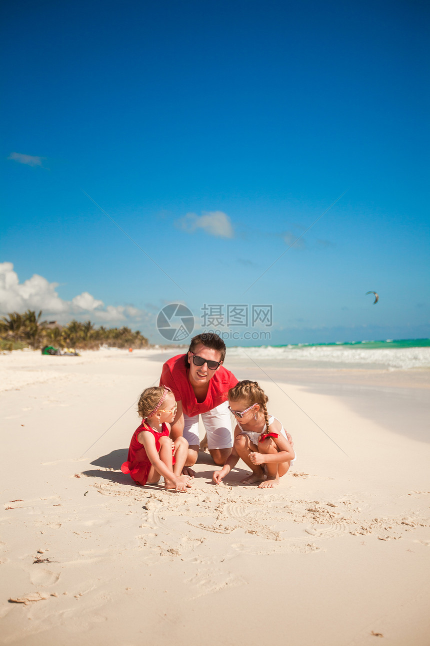 父亲和他的可爱女儿们 在海滩上玩耍 在沙滩上玩父母女孩成人海洋男性幸福热带爸爸女儿享受图片