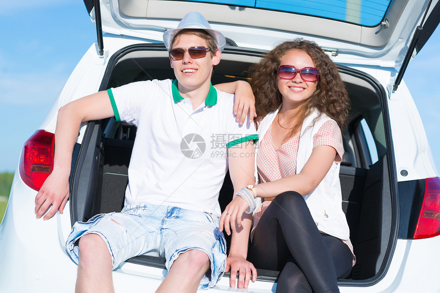 年轻夫妇坐在露天后备箱成人男性车轮天空旅行衣服女性快乐女士运输图片