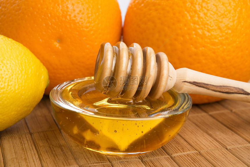 含柠檬和橙子水果的新鲜蜂蜜食物木头漏勺金子早餐甜食黄色甜点玻璃勺子图片