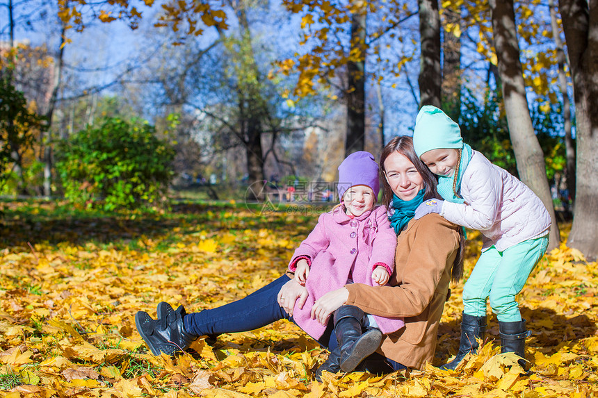 年轻母亲和可爱的女儿们 在阳光温暖的日间秋天公园图片