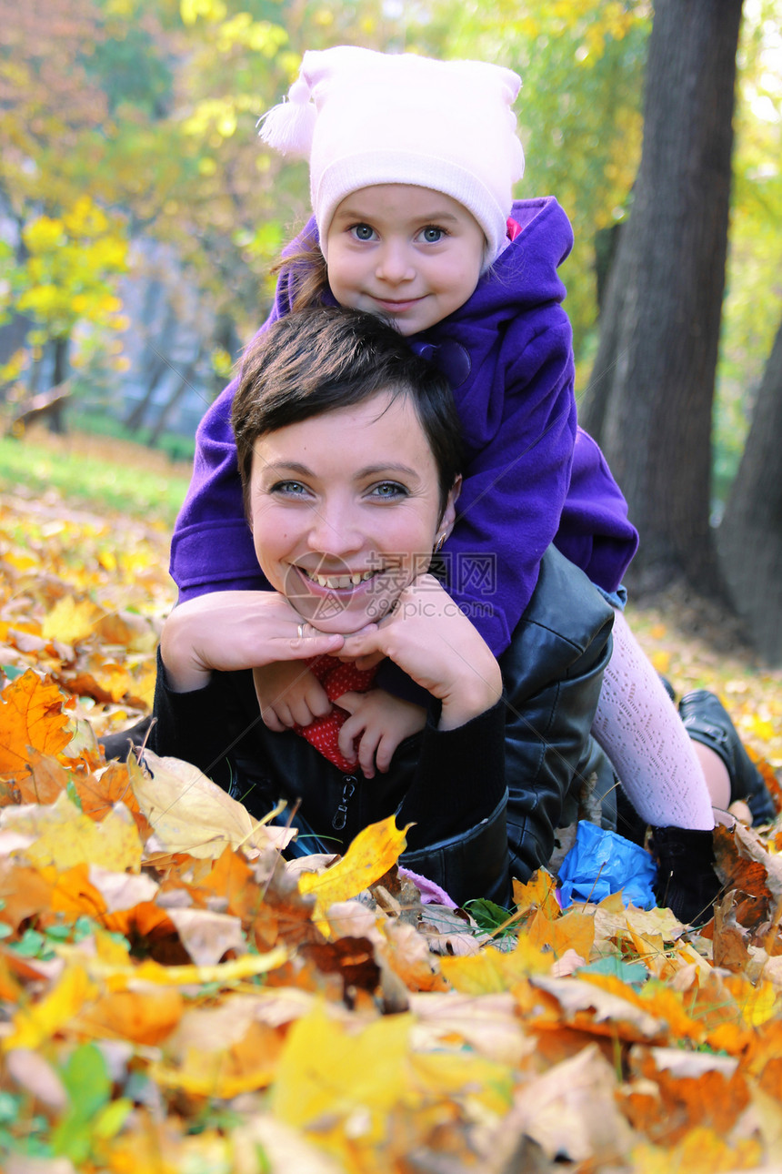 母亲和小女儿躺在秋天的树叶上图片