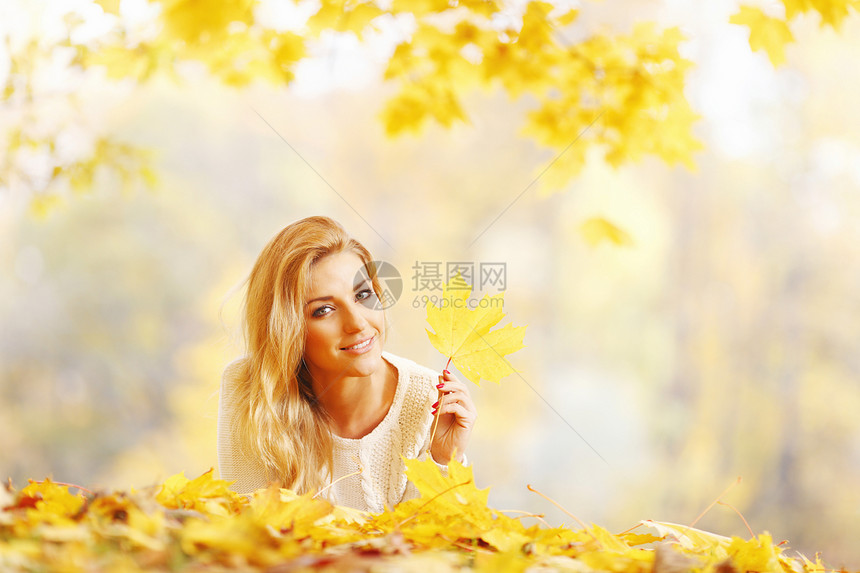 女人躺在秋天公园森林黄色金发闲暇叶子微笑说谎乐趣女性喜悦图片