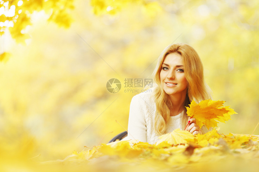 女人躺在秋天公园森林女性闲暇女士乐趣说谎喜悦叶子黄色金发图片