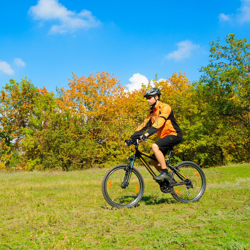 赛车员在美丽的秋季森林中骑自行车下坡闲暇男性爬坡橙子蓝色骑士运动乐趣竞赛图片