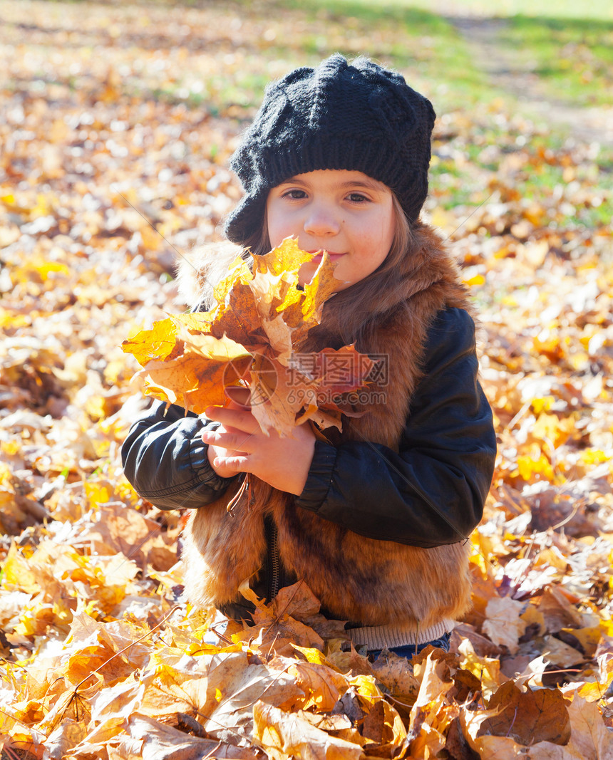 小女孩坐在草地上 保持着一片山坡的秋叶图片