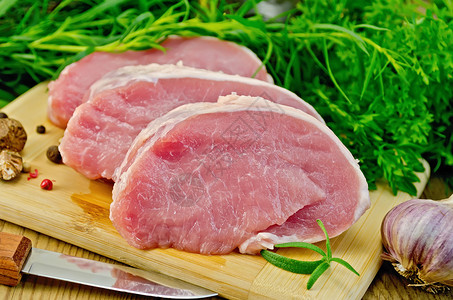 吊龙牛肉带绿菜的板子上的肉猪肉切片背景