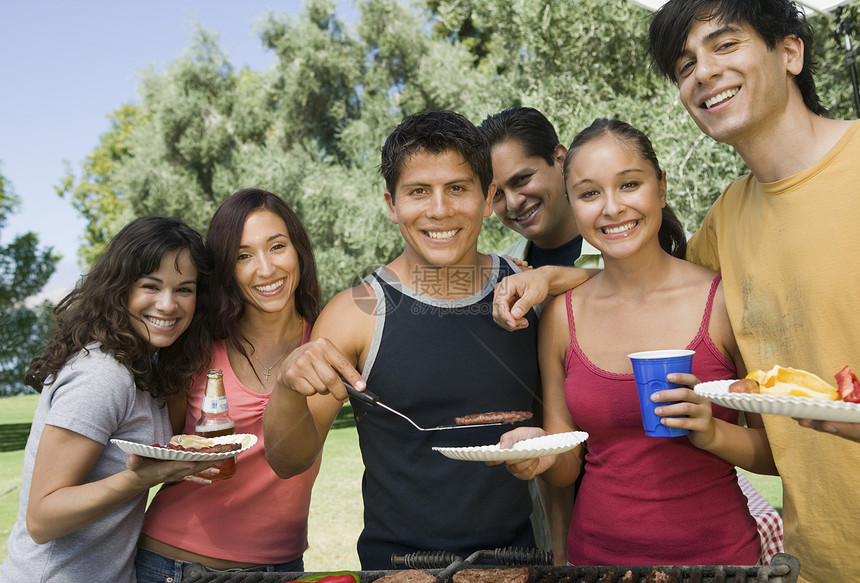 一群年轻人聚集在户外野餐的烤架周围图片