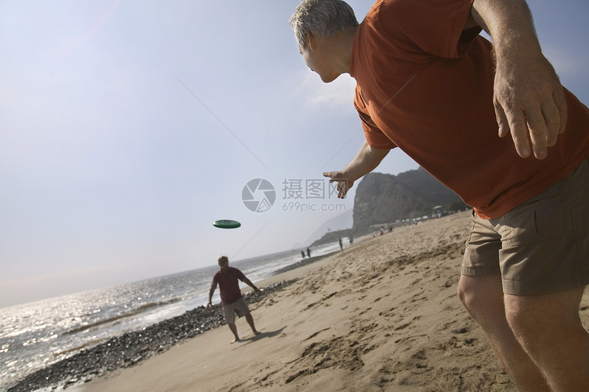 两个男人在海滩上玩飞盘图片