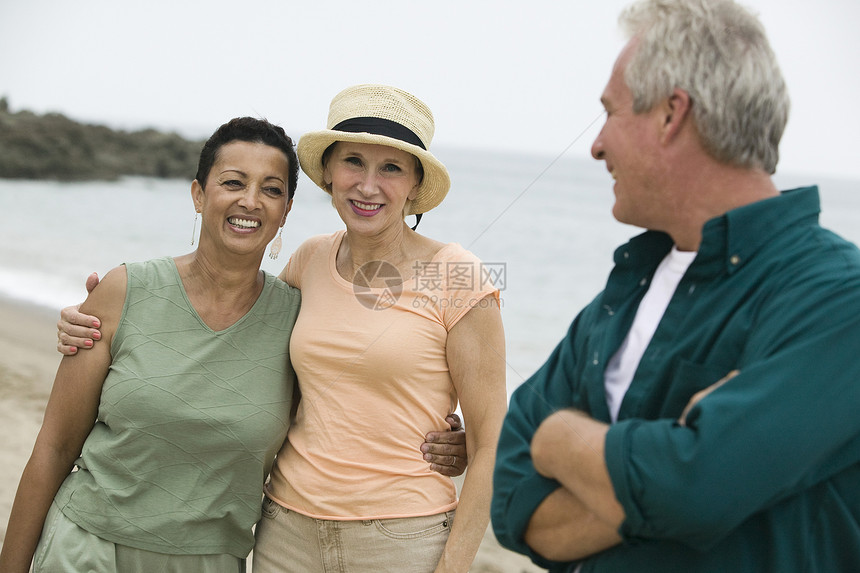 海滩上三个朋友眼神享受友谊服装假期男子休闲中年微笑女性图片