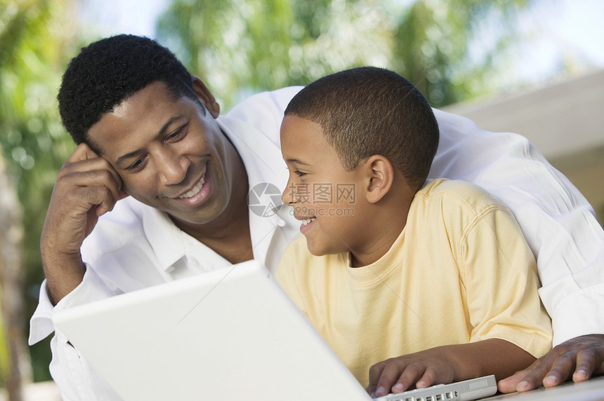 快乐的父亲和儿子一起用笔记本电脑图片
