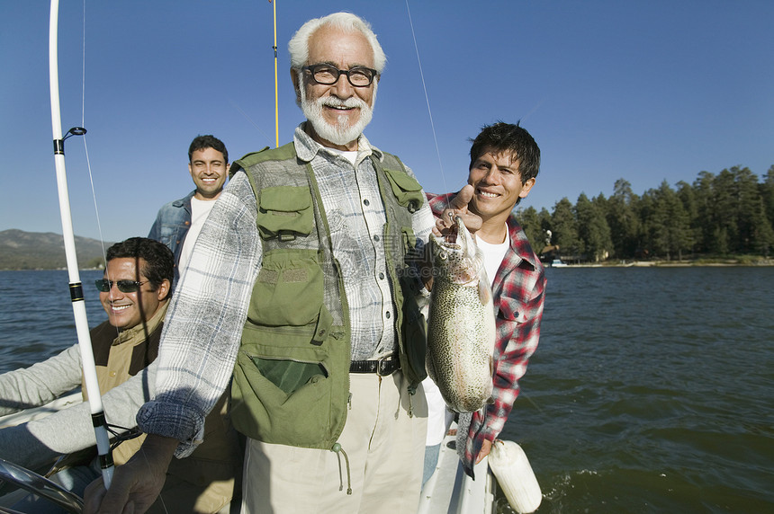 快乐的老年男子与背景中儿子一起抓新鱼的肖像图片