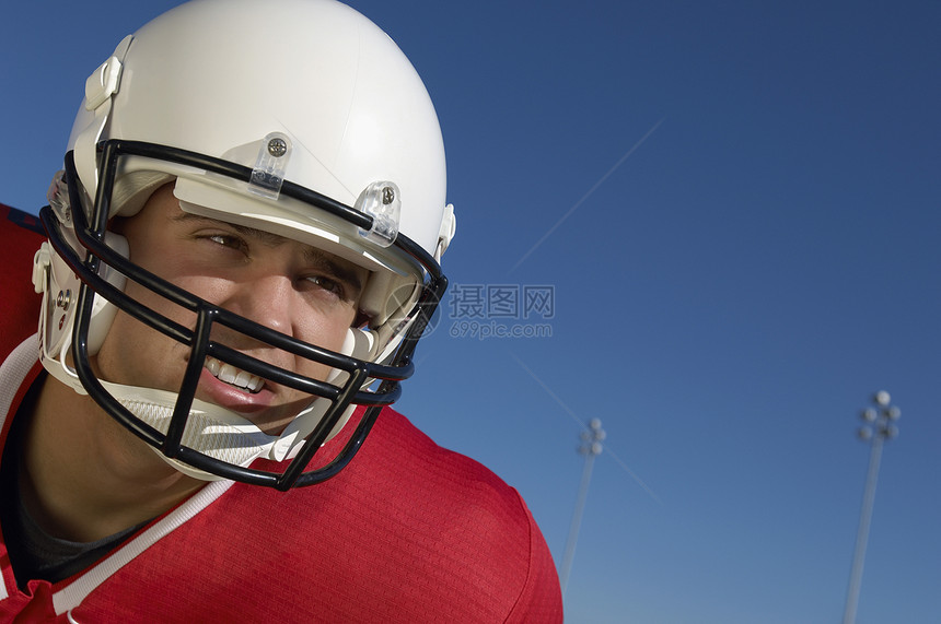 年轻橄榄球运动员穿运动服对抗蓝天图片