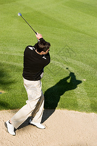 一名年轻男子从沙坑中打高尔夫球背景图片