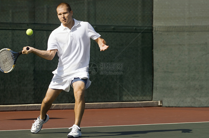 男性网球运动员在网球场前手运动中挥棒打网球图片