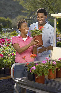 咧嘴笑的男士非洲裔美裔快乐夫妇在高尔夫卡特上装满了陶工厂背景