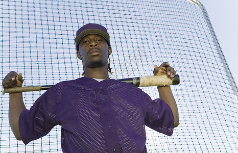 严肃素材网一个充满自信的棒球运动员在练习时拿着球棒与网对打的肖像背景