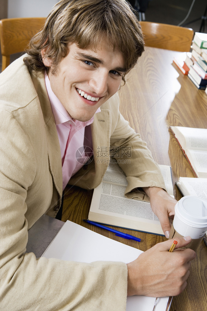 一位快乐的年轻大学生在图书馆书桌学习的肖像图片