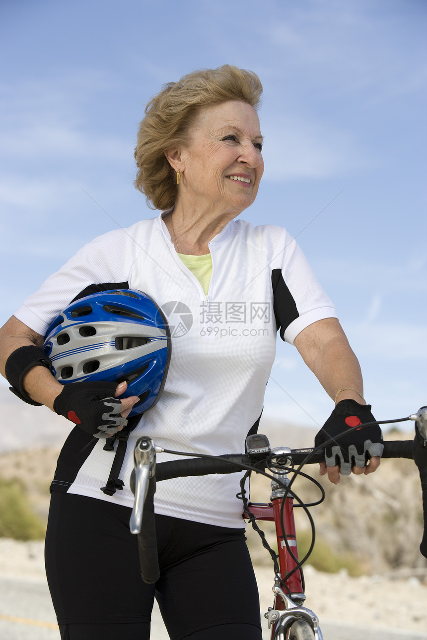 一个快乐的年长妇女的肖像 站在自行车旁看远方图片