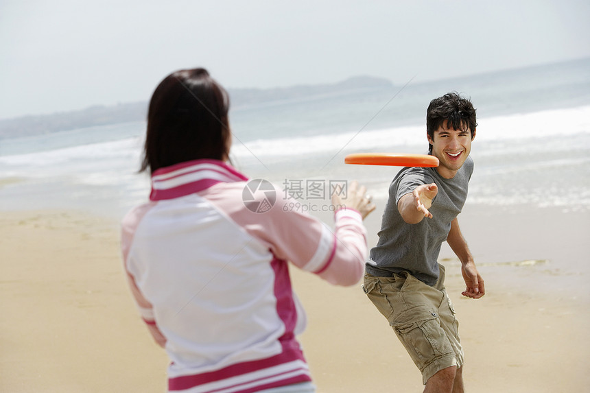 在海滩玩飞盘的年轻夫妇图片