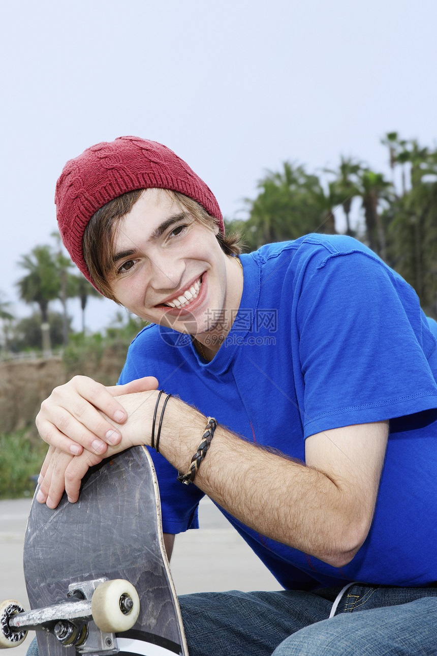 带着滑板微笑的快乐青年男子图片