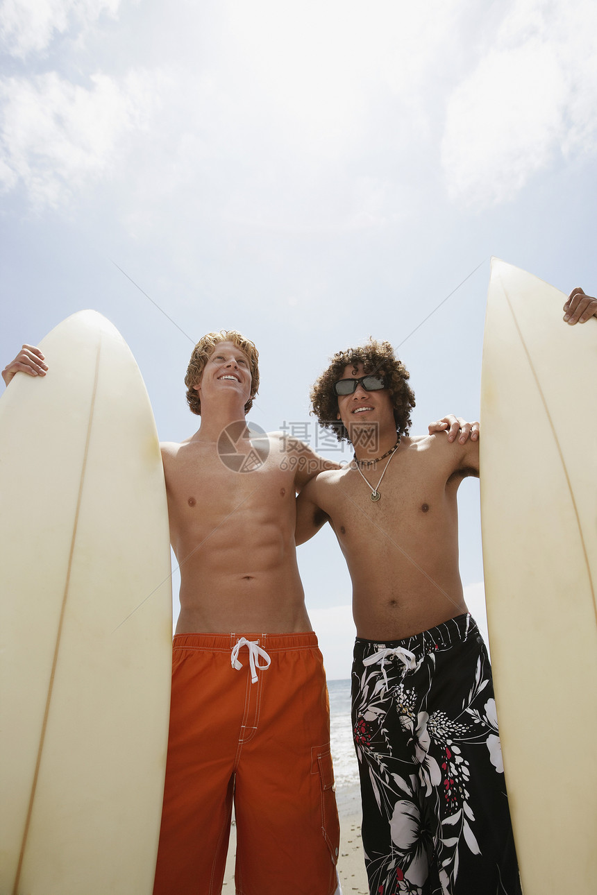 快乐的年轻男性朋友与冲浪板 在阳光明媚的日子图片