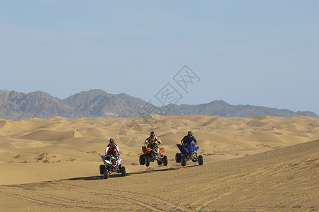 三个赛车同时尼塞三个男人在沙漠连续骑四轮自行车背景