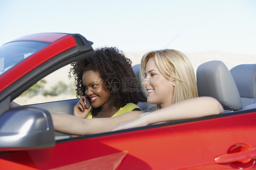 两名青年妇女驾驶红色可兑换车图片
