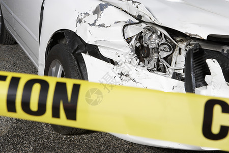 机动车事故在事故现场的警示磁带后面 紧闭一辆被割伤的汽车背景