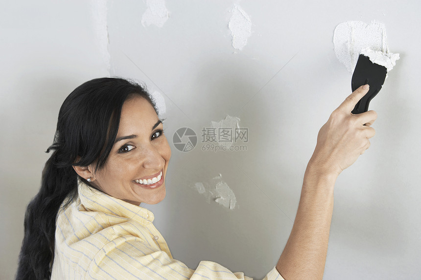 快乐的中年女性在墙上涂抹油图片