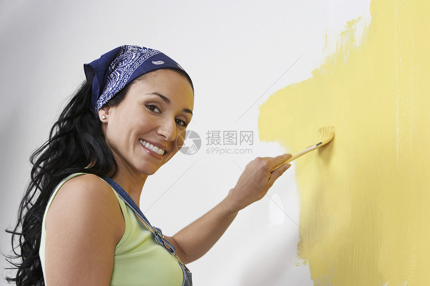 一位快乐的年轻女人的侧边景色 在墙上画着黄色图片
