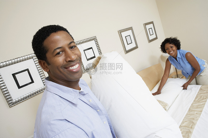 一名非洲裔美国人男子与妇女一起用枕头在家里安排床铺的肖像图片