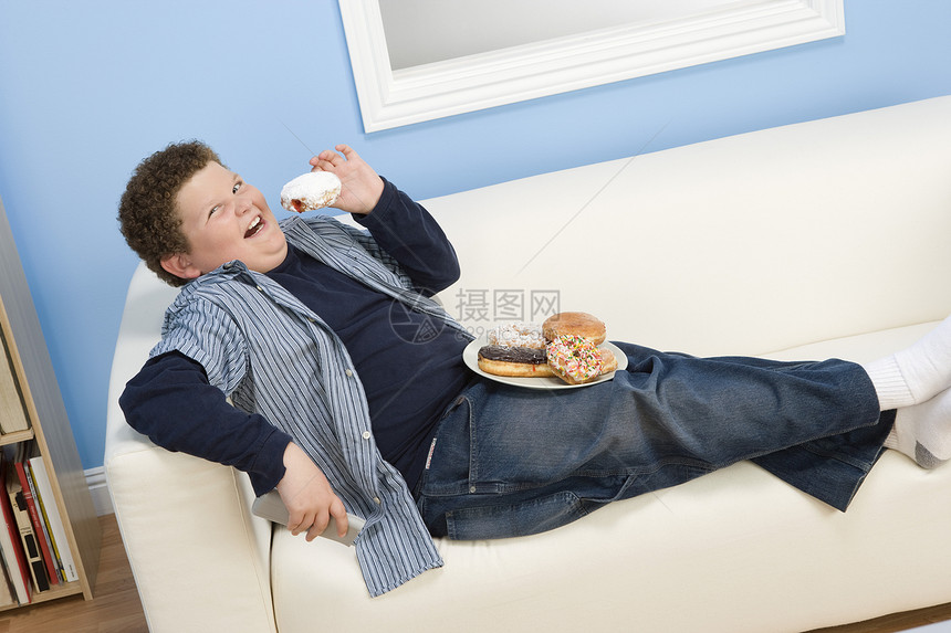 玩耍吃甜甜圈男生男性饮食电视孩子们肥胖男孩青春期沙发青少年图片