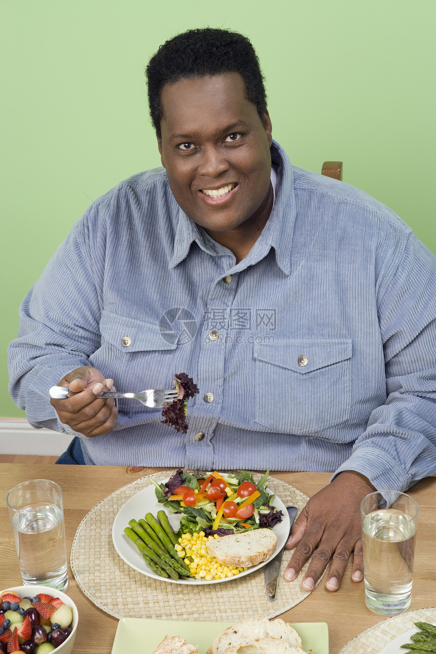 一个快乐的肥胖男人在家吃健康食物的肖像图片