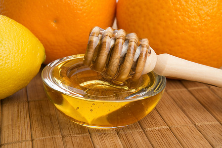 含柠檬和橙子水果的新鲜蜂蜜液体勺子漏勺餐具黄色玻璃生活方式早餐甜食美食家背景图片