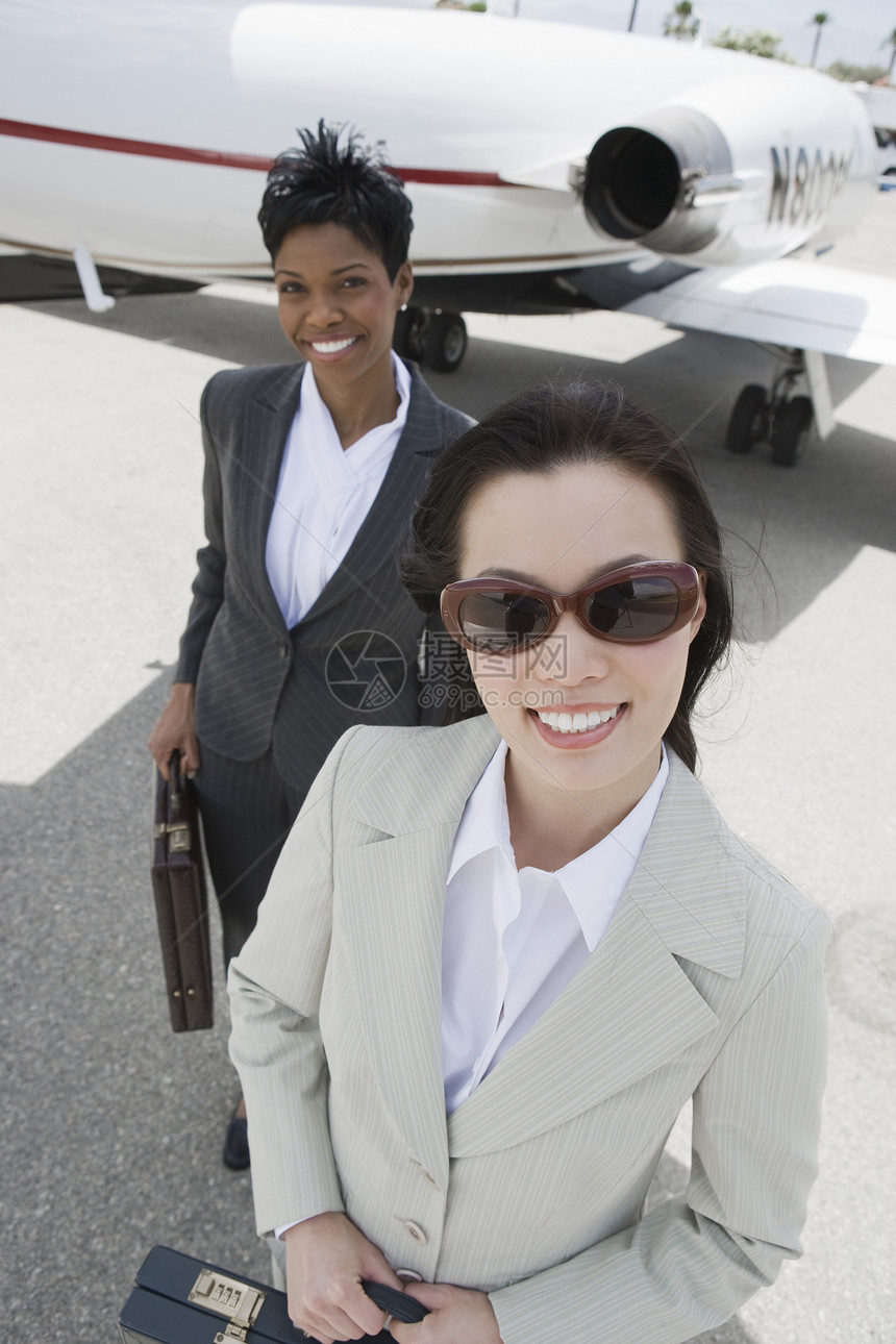 一名成功的商业女商务人士的肖像 其同事与飞机在机场背景中的背景相配图片