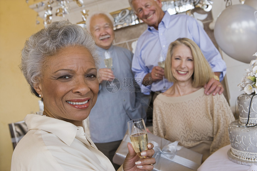 一位非洲裔美国高龄女性的肖像 她拿着香槟杯与朋友在自己的背景中图片