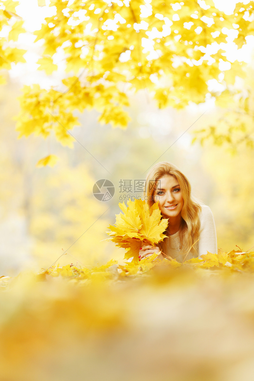 女人躺在秋天公园喜悦说谎乐趣橙子闲暇女性微笑快乐金发黄色图片