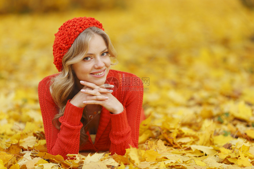 女人躺在秋叶上金发森林喜悦女性橙子帽子金子公园红色叶子图片