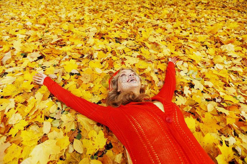 女人躺在秋叶上幸福红色乐趣金子叶子女性微笑女孩橙子金发图片