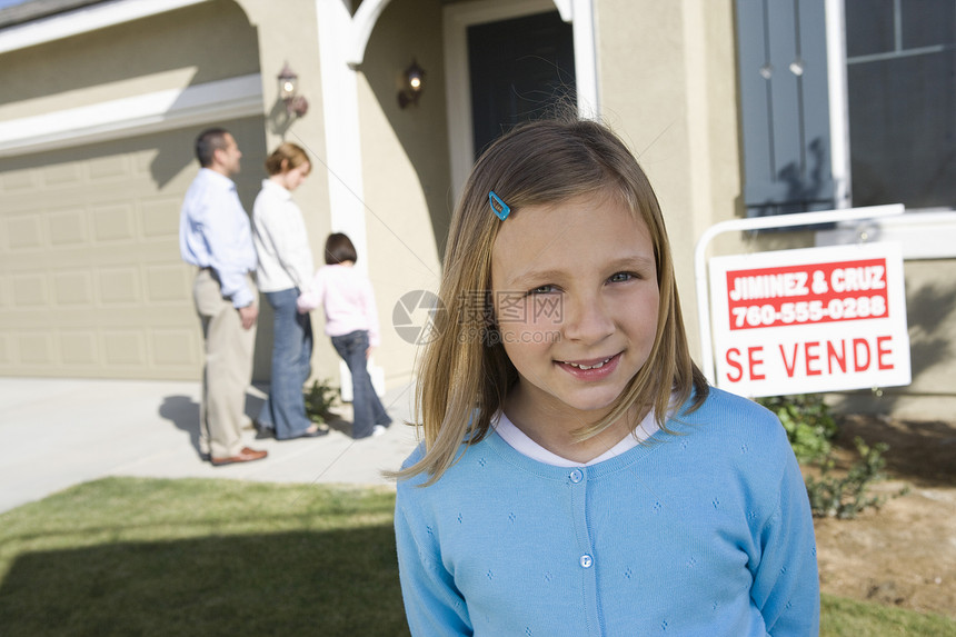 家庭站在房子门前卖掉的快乐女孩的肖像图片