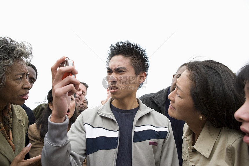 愤怒的青年男子在人群中持有手机图片