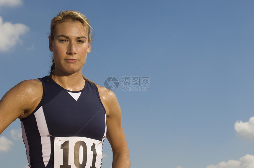 一名自信的女性运动员在运动服上对抗天空的肖像图片