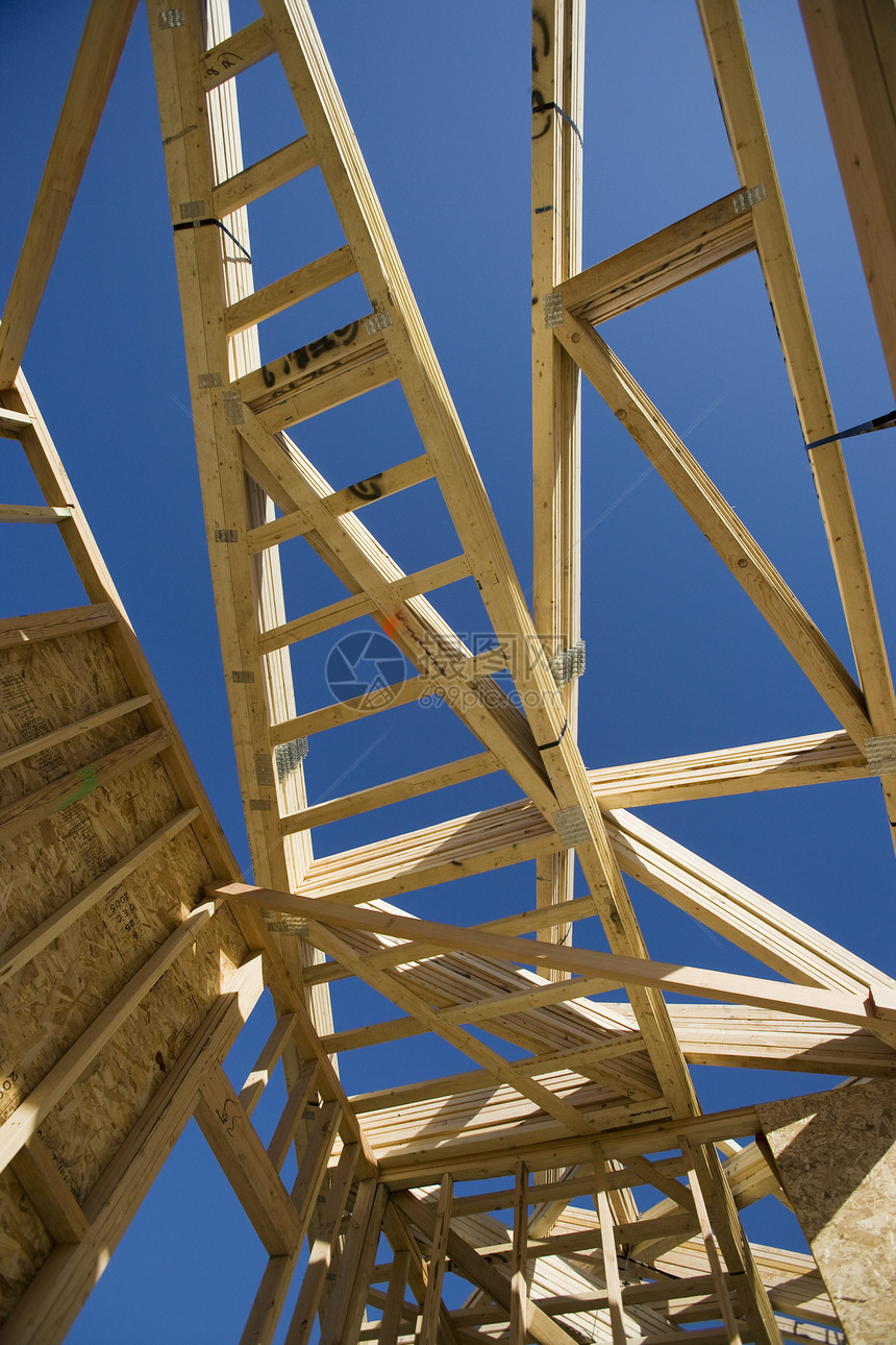 一座未完工房屋建筑框架对蓝色天空的低角角度视图以蓝天为对比建筑学建造工地房子光束图片