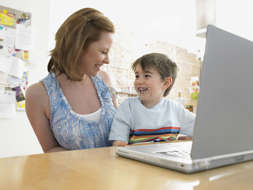 幸福的母亲和儿子 用笔记本电脑看着每家每户图片