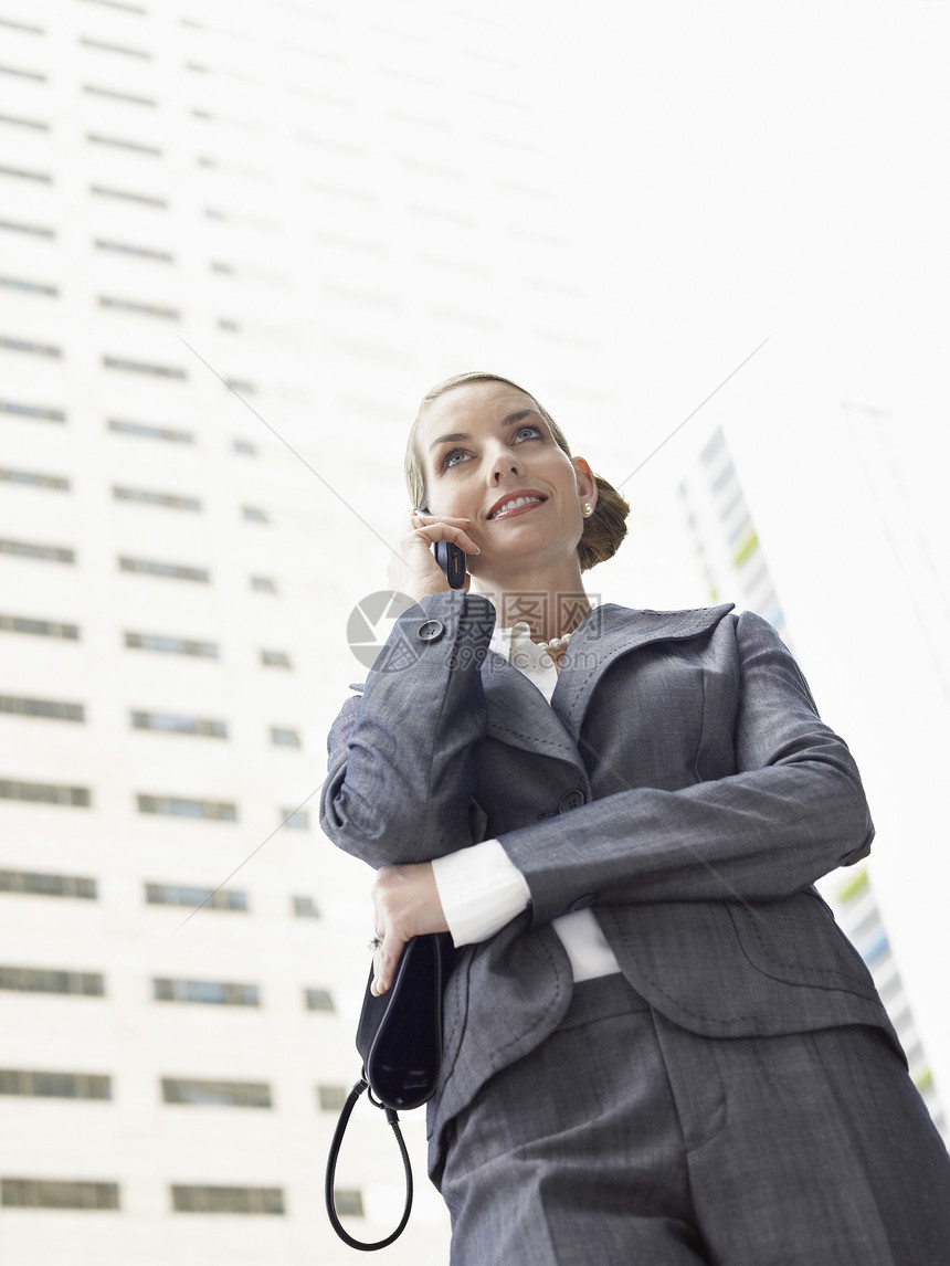 商业妇女对高楼办公大楼使用移动电话交谈的低角度视角视野(百分比)图片