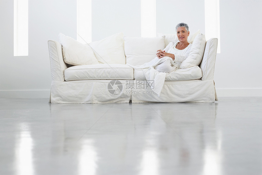 在宽敞的房间里坐在沙发上的高级妇女全长肖像公寓客厅退休婴儿成人微笑女性短发水平幸福图片